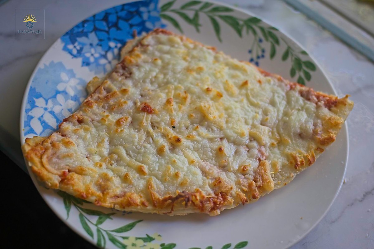Air-fried frozen pizza on a rustic plate in warm kitchen light