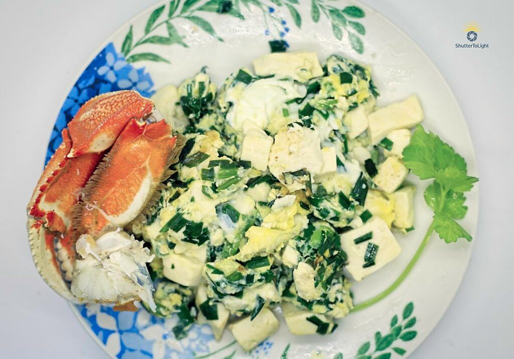 Home-cooked tofu scramble with Dungeness crab and eggs, served on a plate